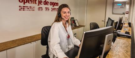 Medewerker achter balie met headset op